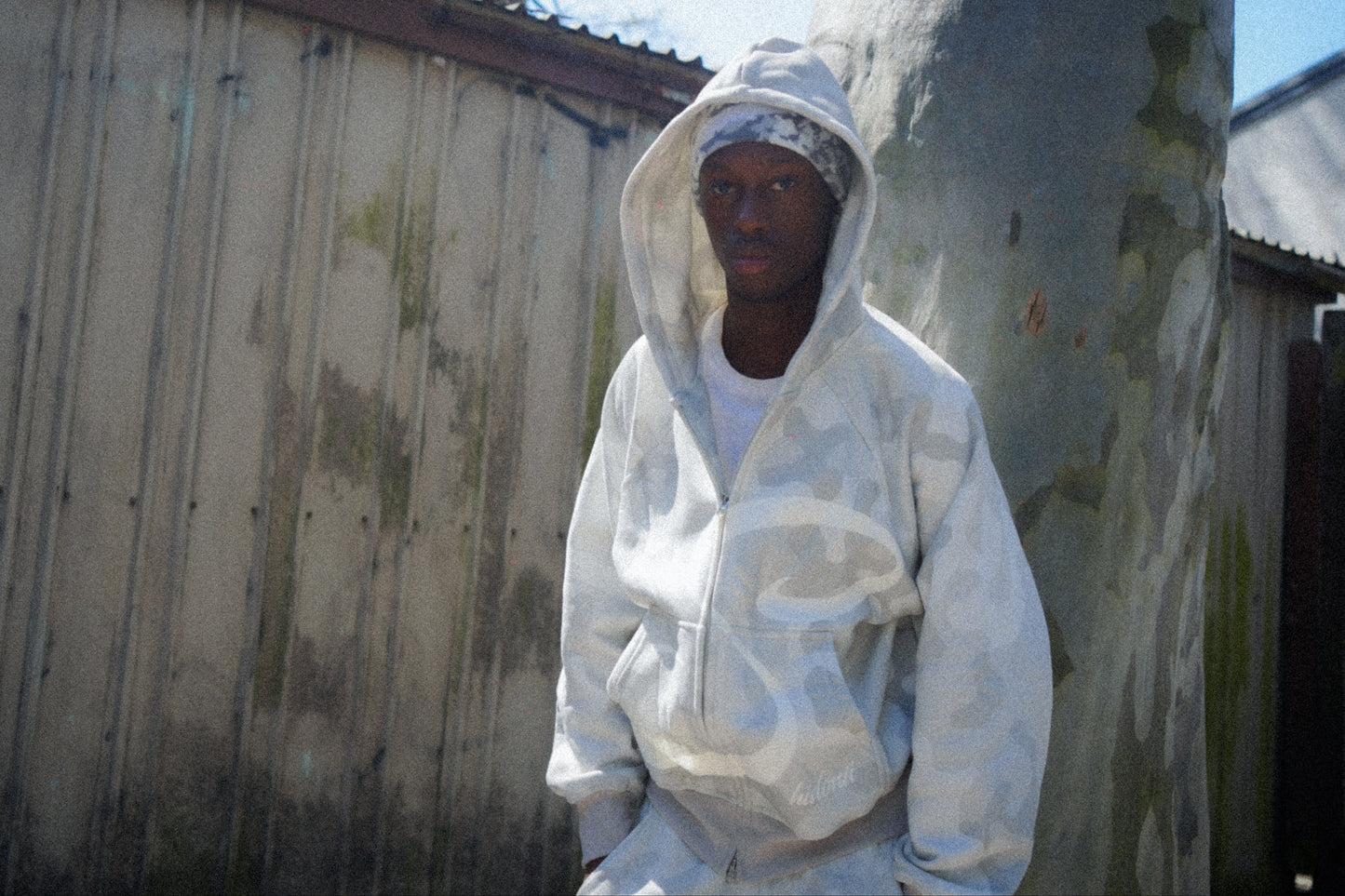 Person wearing a white protective suit standing against a weathered wall.