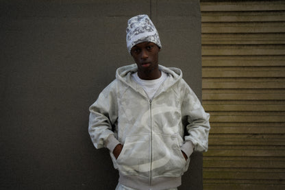 Person wearing a camouflage hoodie and beanie against a plain background