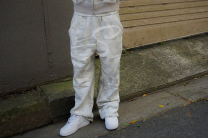 Person wearing a camouflage tracksuit standing on a sidewalk.